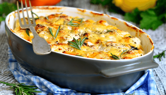 Receita de Filé de Frango ao Creme de Batata com Queijo, servido em um refratário cinza e um garfo grande em cima da lateral do refratário